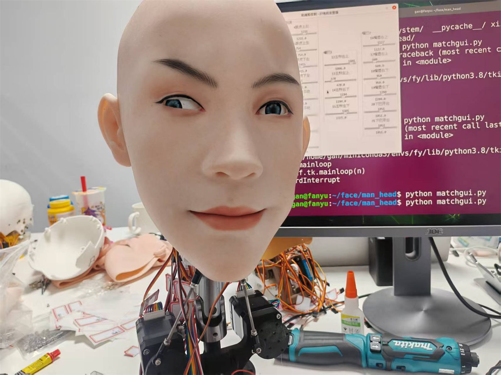 Bald silicone head on the bench with a live control GUI on the monitor behind it