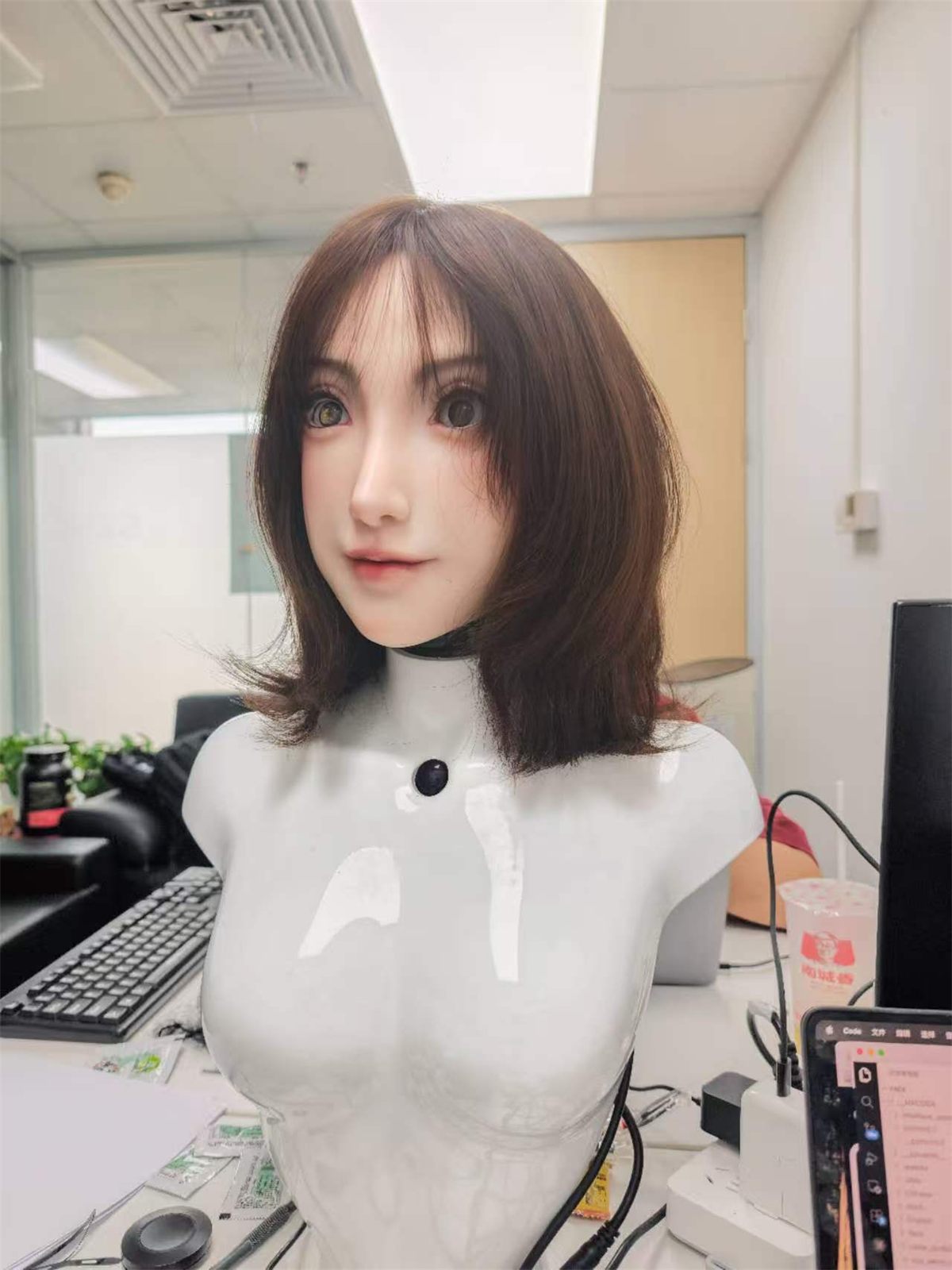 Current Elva unit with brown hair on a white bust, sitting on an office desk
