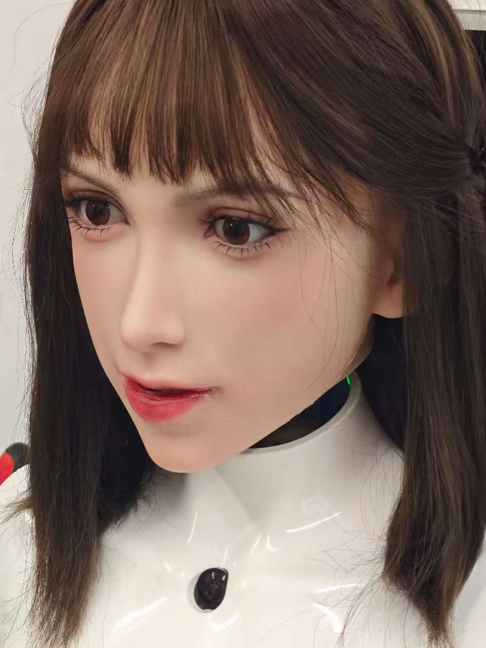 Three-quarter close of the current Elva face, brown hair, black collar, white bust